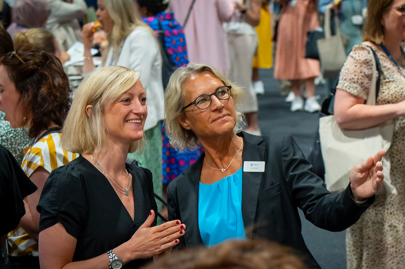 Projektledare som visar något för kund i folkmingel på konferens