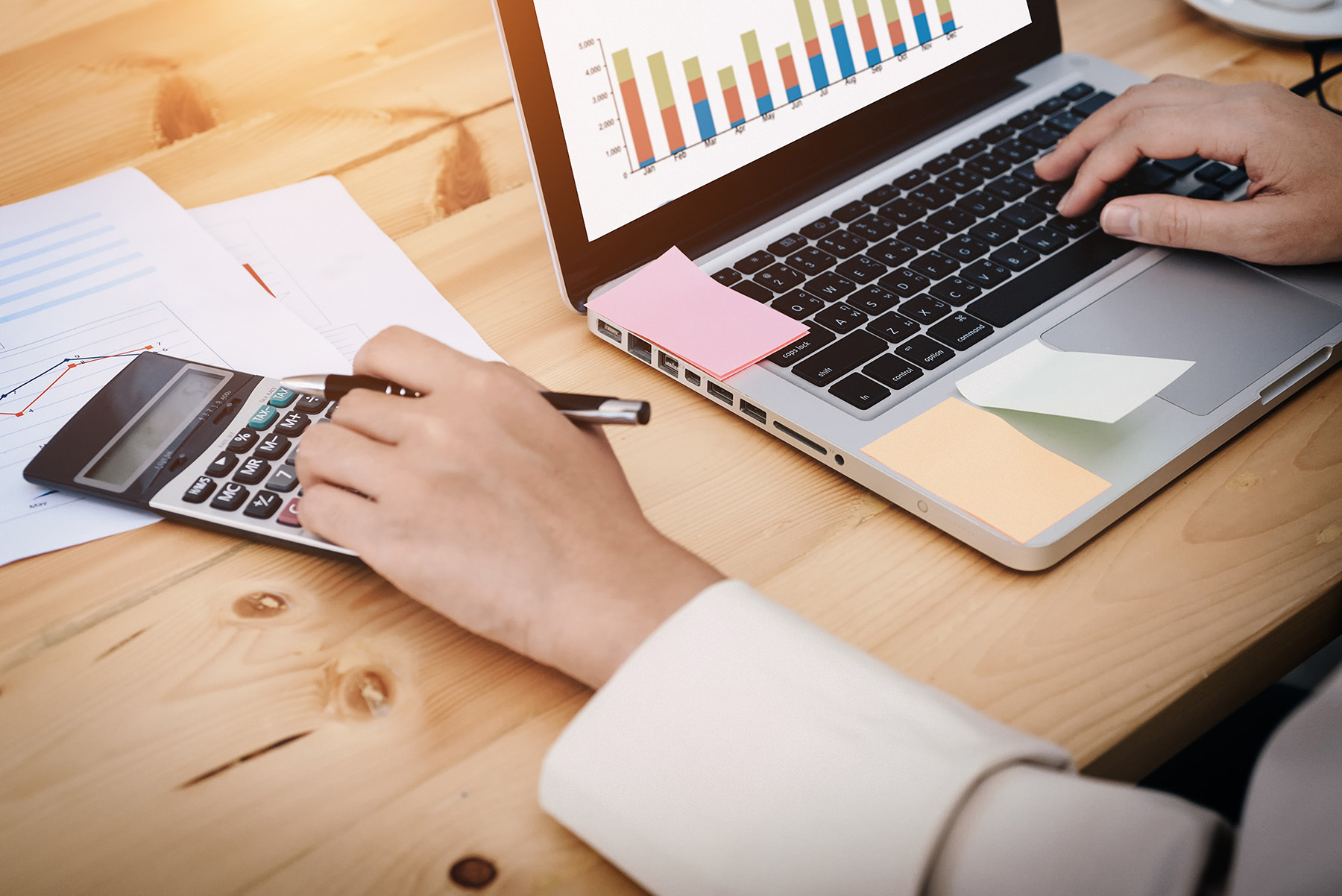 Händer som jobbar med en dator och miniräknare.